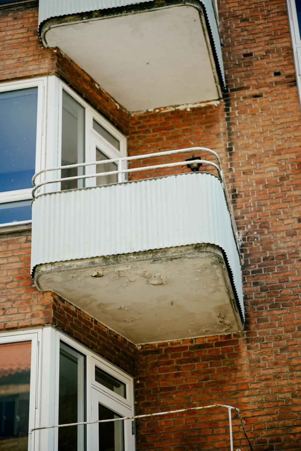 Eksisterende betonaltaner med synlige skader på undersiden